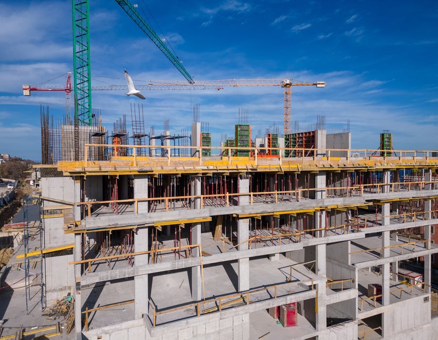 Edifício em estrutura de concreto armado durante a construção, com grua ao fundo