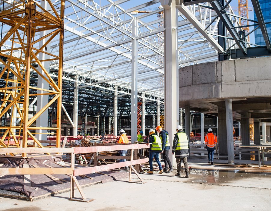 Galpão industrial com estrutura metálica em montagem e equipe de obra no piso