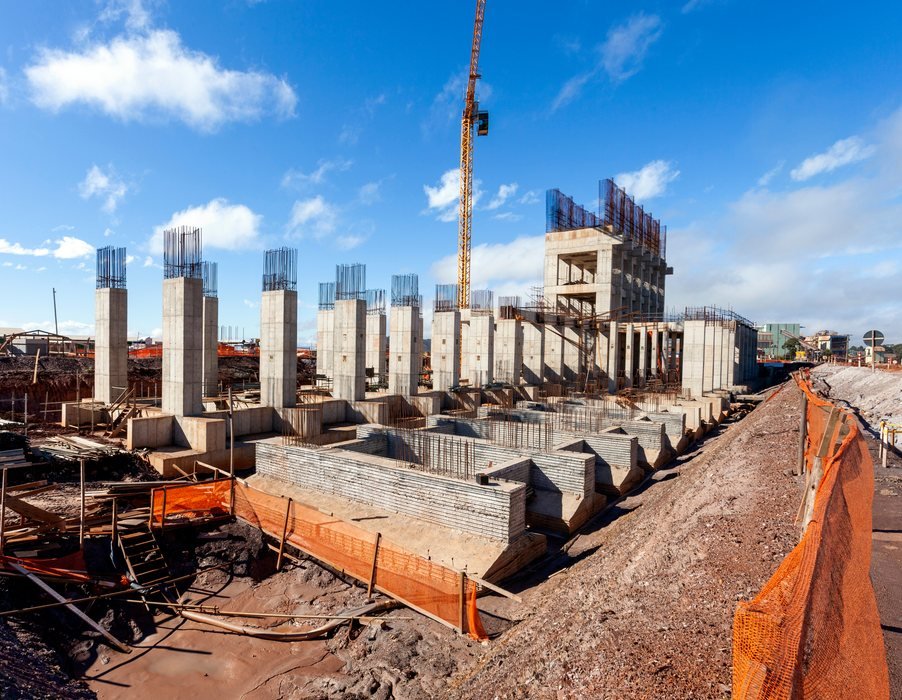 Canteiro de obras com pilares de concreto e fundações executadas a céu aberto