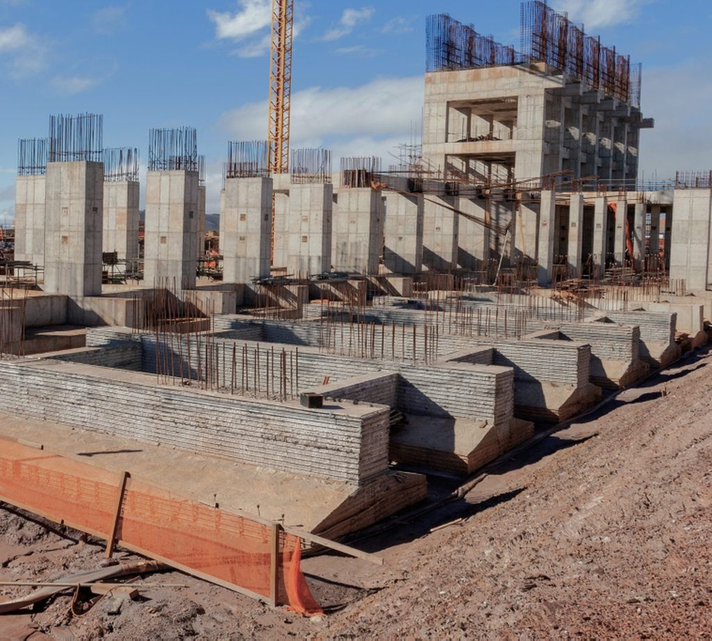 Estrutura de concreto armado de um edifício em construção com grua ao fundo
