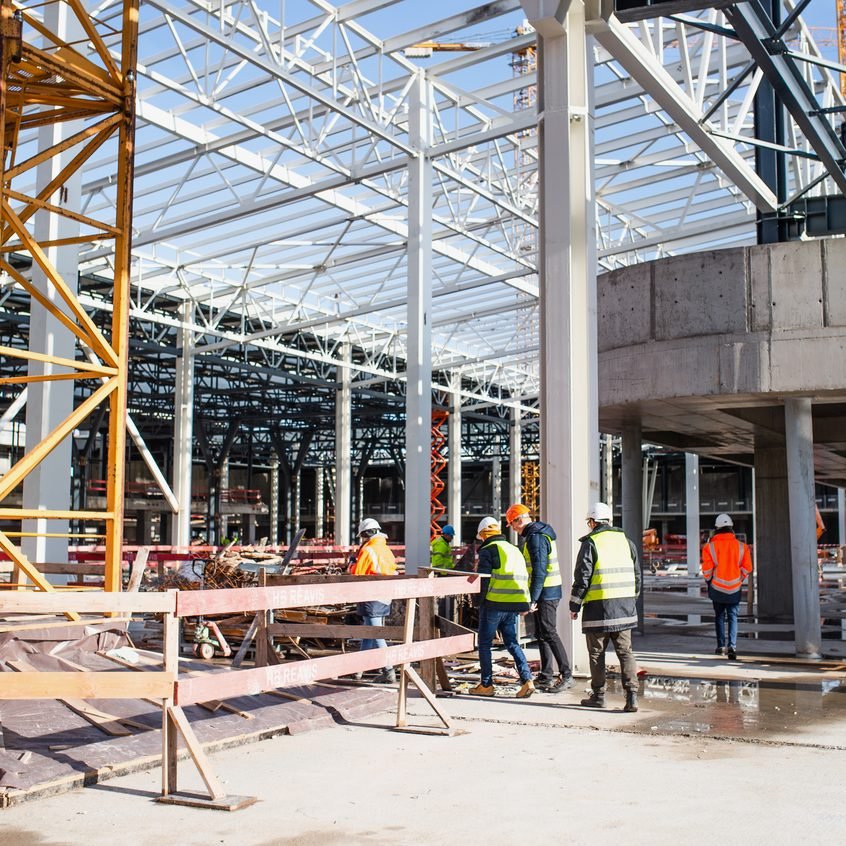 Equipe de obra alinhando processos no pavimento de uma estrutura em construção